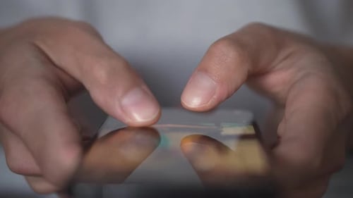 A Young Man Uses a Smartphone to Write and Send Message Closeup