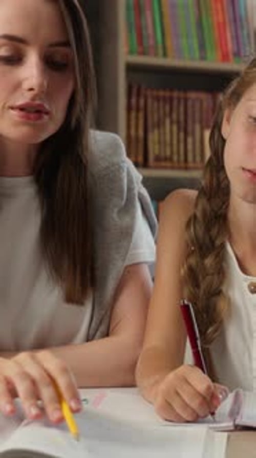 Woman Helping Girl with Homework at Desk