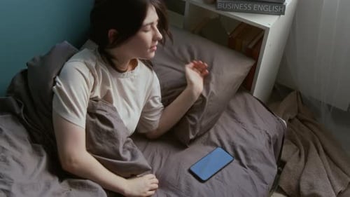 Jovencita morena despertándose y cogiendo el teléfono