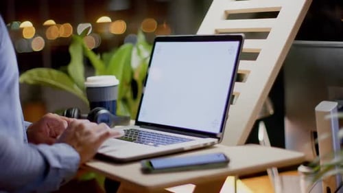 Midsection of biracial businessman using laptop with copy space in office at night, slow motion