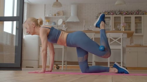 Woman Exercising with Dumbbell in Kitchen