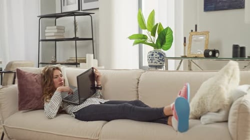 Woman Using Laptop While Lying on Sofa