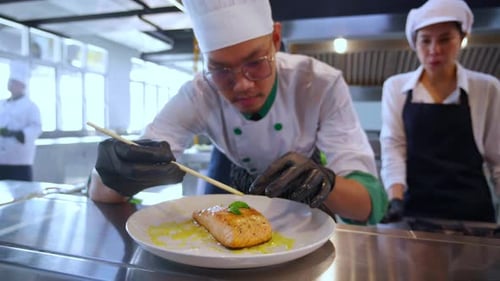 Chef Carefully Garnishing Salmon Dish in Restaurant Kitchen