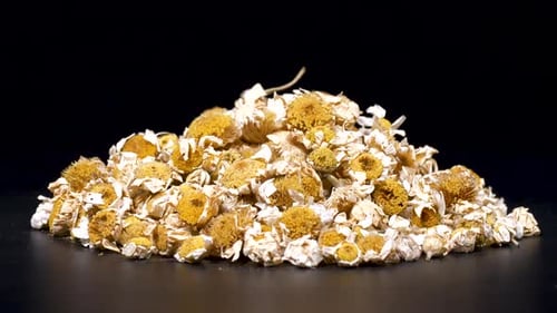 Pile of Dried Chamomile Flowers on Black Background