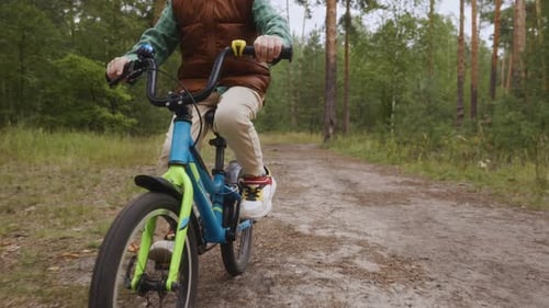Low Angle Front View Boy Cycling on Forest Path