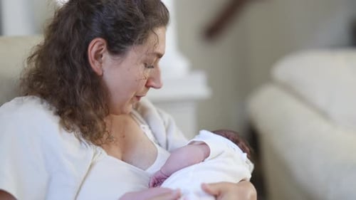 Woman holding infant baby in her arms indoors