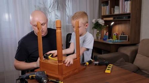 A Little Boy and His Father are Repairing or Assembling a Chair at Home