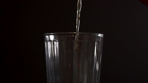 Pouring beer into a glass creating lots of foam, close up slow motion