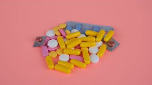 Colorful Pills and Capsules on Pink Background