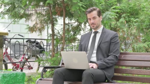 Empresario de mediana edad en negación mientras trabajaba en una computadora portátil al aire libre