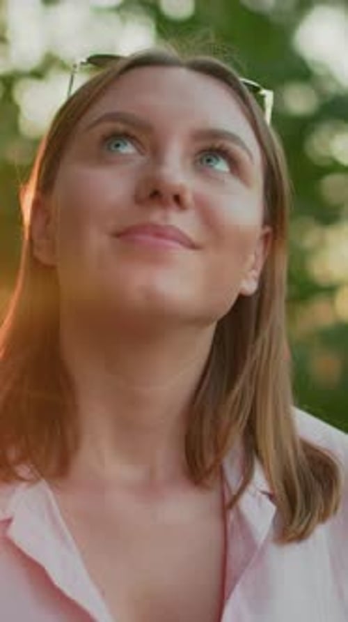 Belle dame souriante et levant les yeux pensivement dans la lumière extérieure naturelle