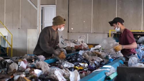 Workers Sorting Garbage Moving Down The Belt At A Recycling Plant