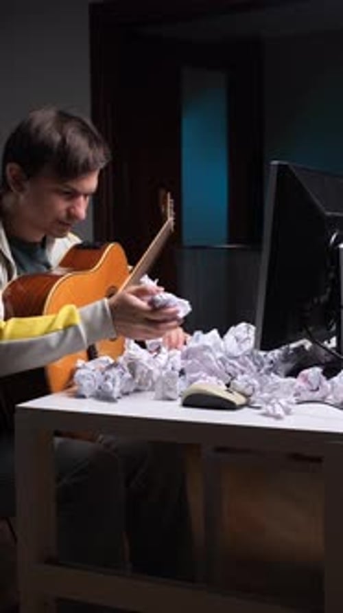 Musician with Guitar Surrounded by Crumpled Papers