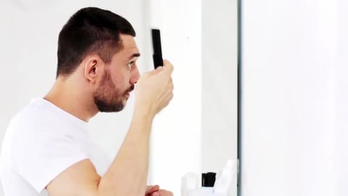 Man Combs Dark Hair in Bright Bathroom
