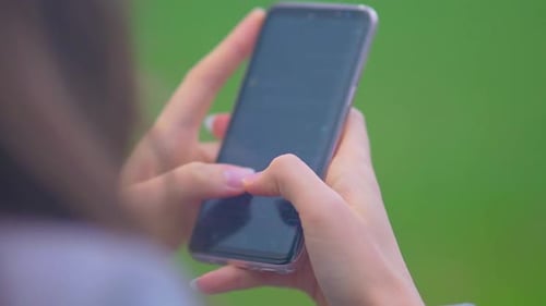 Woman's Hand Typing Message On Cellphone. - close up