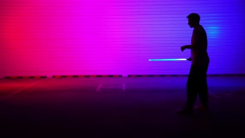 A Striking Silhouette Wielding a Blue Light Saber Set Against a Vibrant Colorful Background Media