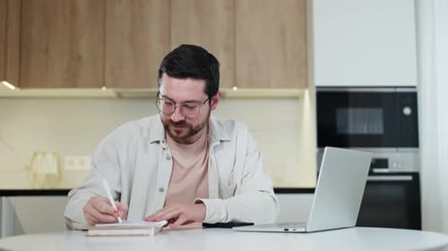 Man Works At Home With Laptop and Notebook