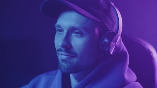 gamer in headphones and cap playing and smiling, thumb up