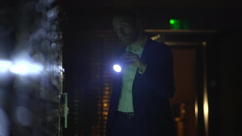 Man Inspecting Wall With Flashlight at Night