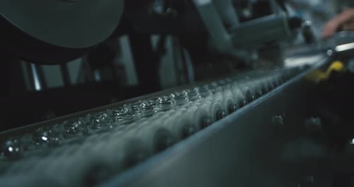 Capsules Moving Along Conveyor Belt in Factory Machine