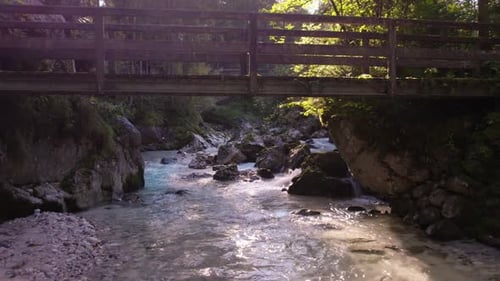 Prise de vue aérienne par Drone passant sous un petit pont en bois au-dessus d'un ruisseau qui coule à reculons