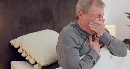 Mature Man Coughing and Clutching Chest in Bed