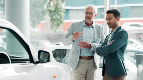 Car dealership, negotiation or retail with customer and salesman on showroom floor for choice