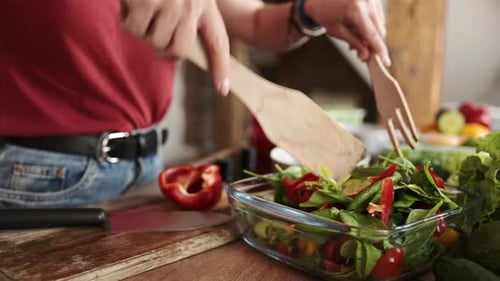 Woman Prepares Fresh Salad with Vegetables in Kitchen