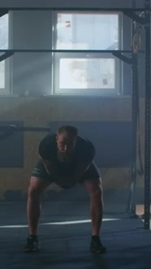 Focused Athlete Performing Powerful Kettlebell Swing Exercise in Dimly Lit Gym Showcasing Strength