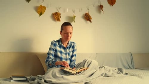Gemütliche Lesestunde mit einer warmen Decke drinnen im Herbst