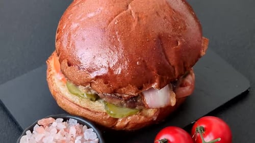 A burger with a patty, cheese, vegetables, and sauce. A burger with meat