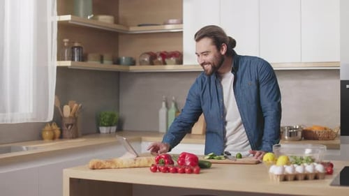 Man Smiles in Kitchen While Cooking with Vegetables