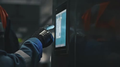 Factory worker using touchscreen control panel in production plant