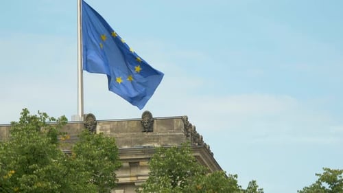 EU Flag Waves atop Building on Sunny Day