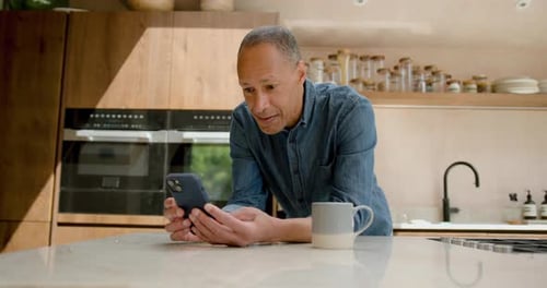 Man Uses Smartphone in Bright Modern Kitchen