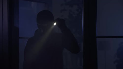 Masked Figure Shining Flashlight Inside a Home at Night