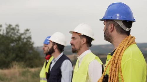 Team von technischen Mitarbeitern, Bauingenieuren und Architekten, die Helm und Weste tragen, arbeiten im Freien