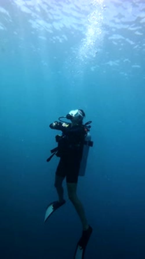 Scuba Diver Ascending in Deep Blue Ocean Water