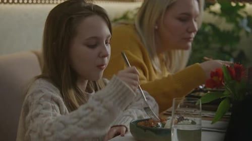 Young Girl Smiles and Eats Tasty Dish in Cafe