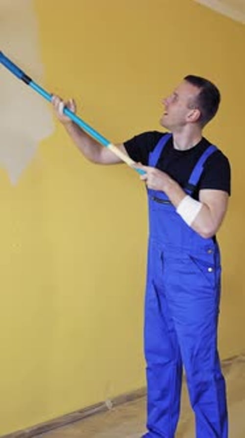 Mann malt Wand mit Farbroller. Junger gutaussehender Mann, der Wand malt, Zimmer renoviert.