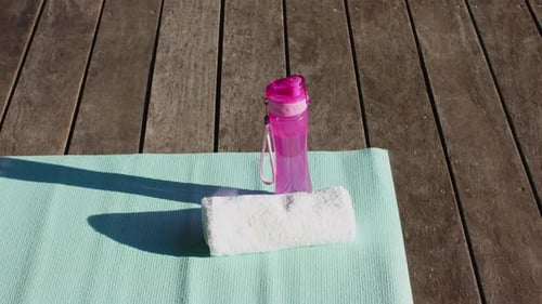 Yoga Mat and Water Bottle on Wood Deck