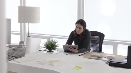 Hispanic businesswoman uses digital tablet at desk in slow motion Canada office