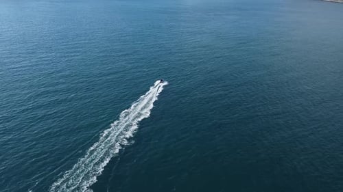 Following a small boat as it speeds through the open ocean.