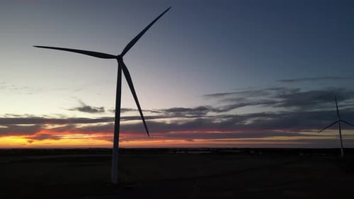 Silhouette of wind turbine spinning at twilight. Aerial drone view and sky for copy space