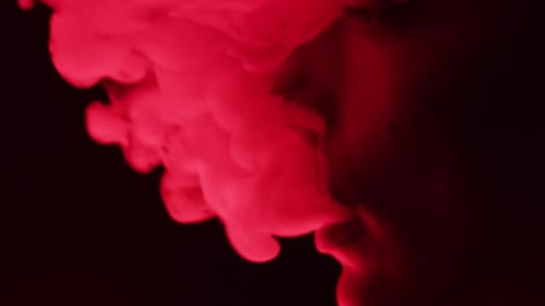 Person Exhaling Thick Red Smoke in Dark Environment