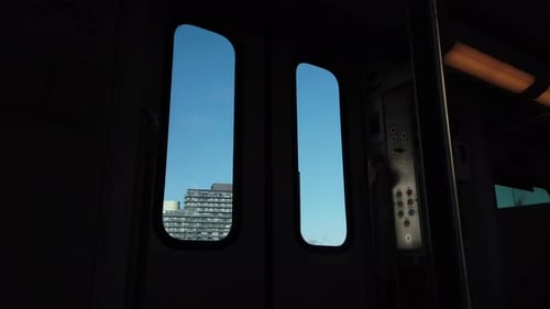 Passenger point of view looking out the door of a moving train at the city landscape passing by