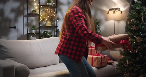 Woman Opens Christmas Gift on Sofa at Home