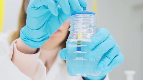 Une chimiste teste une solution pour le pH à l'aide d'un papier indicateur