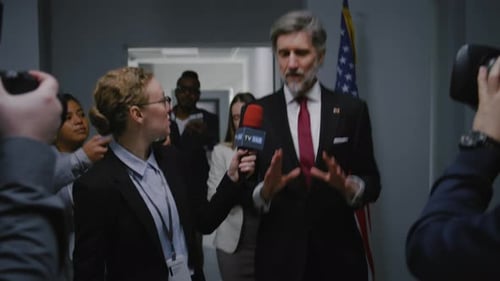 Politician Interviewed by Journalist in Hallway with Cameras