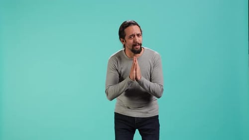 Man Clasping Hands in Front of Blue Backdrop